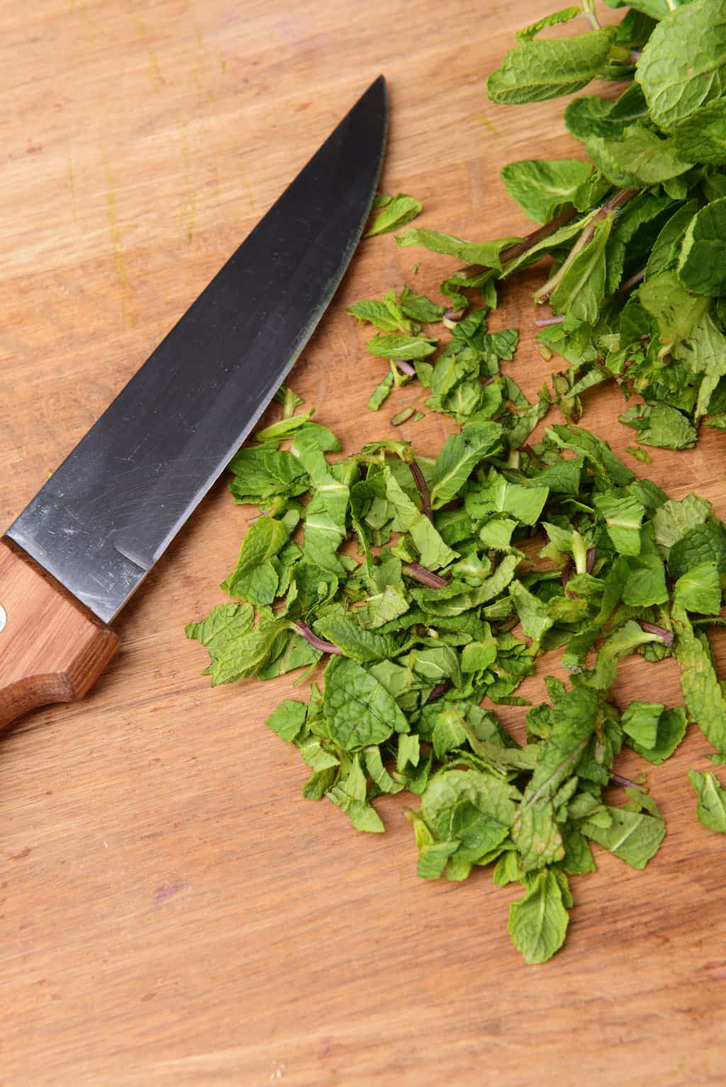 sharp knife and fresh mint on a wood cutting board