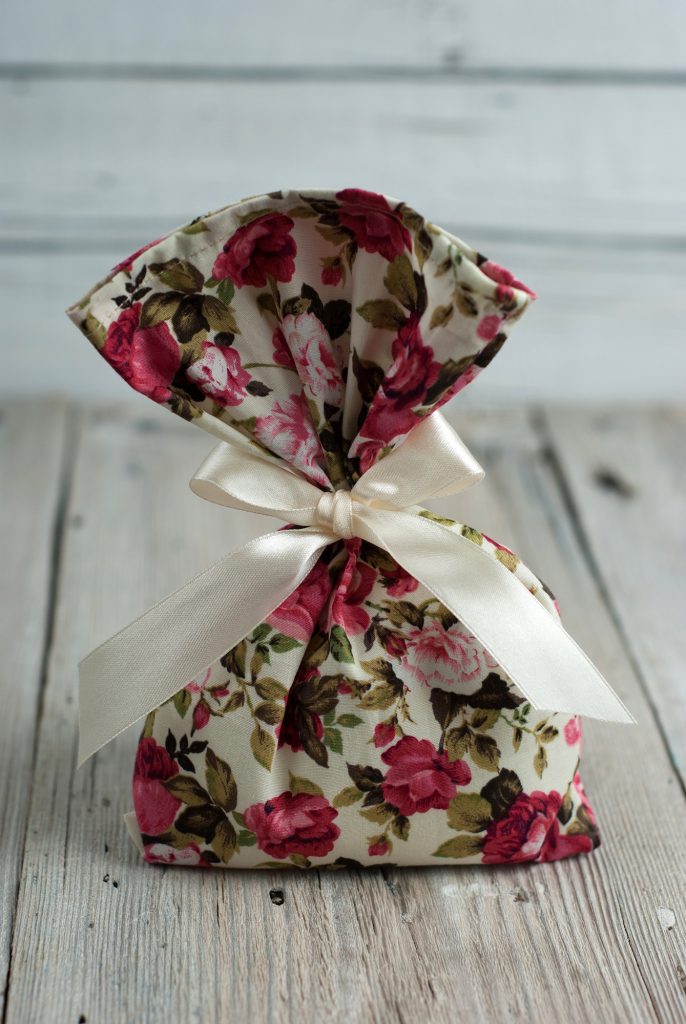 Fabric pouch of dried herbs  tied with ribbon on old wooden table