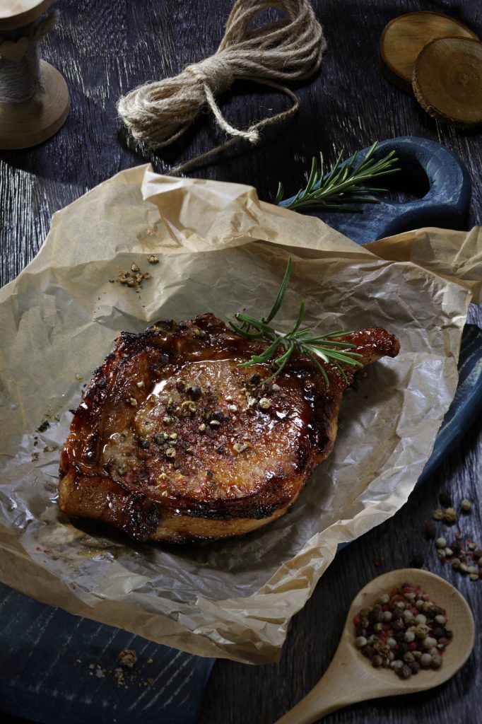 pork chop cooked with rosemary salt on a piece of parchment paper
