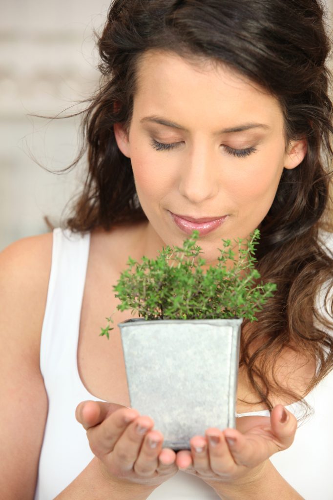 Woman smelling a herb pot